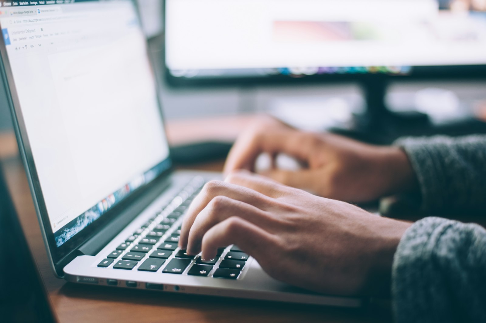 Person writing on a laptop at a bright desk