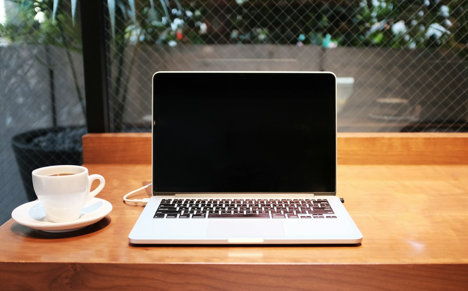 Open laptop on a wooden table with notebooks nearby