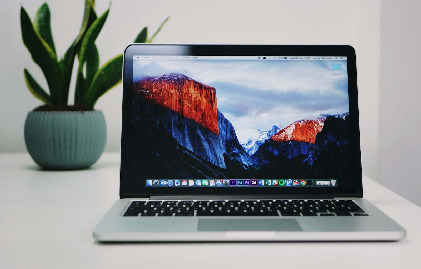 Person using a silver MacBook on a sofa