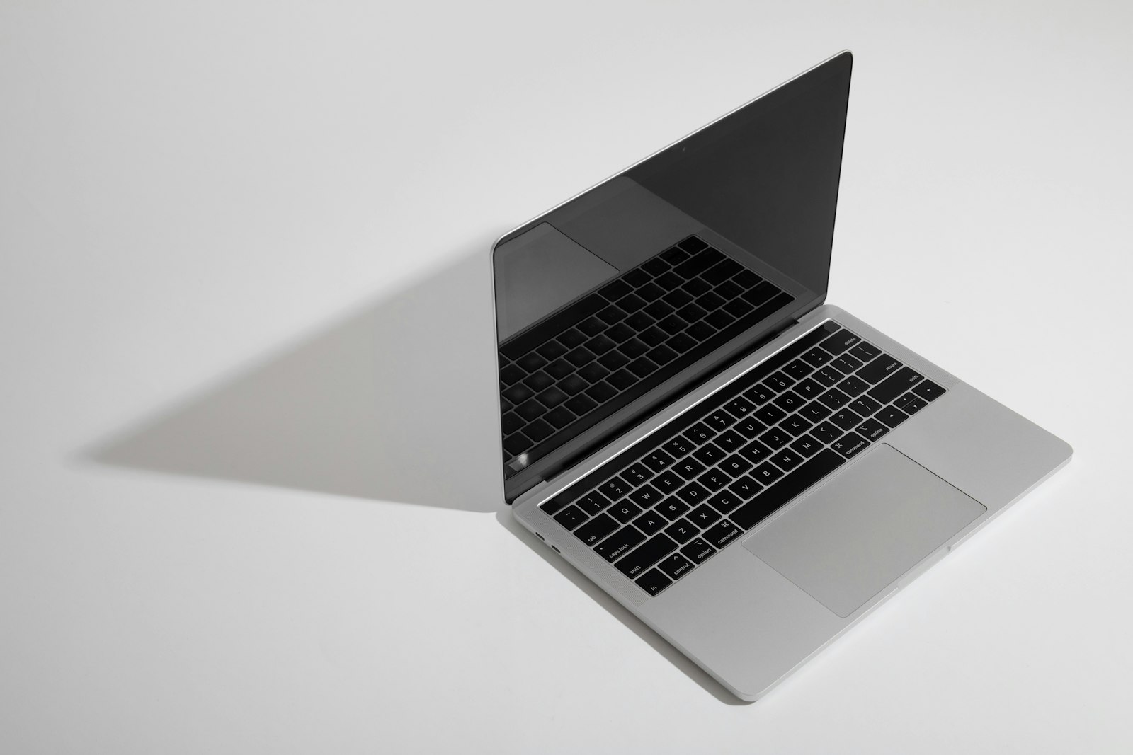 Silver MacBook Air open on a white surface with keyboard reflection in the screen