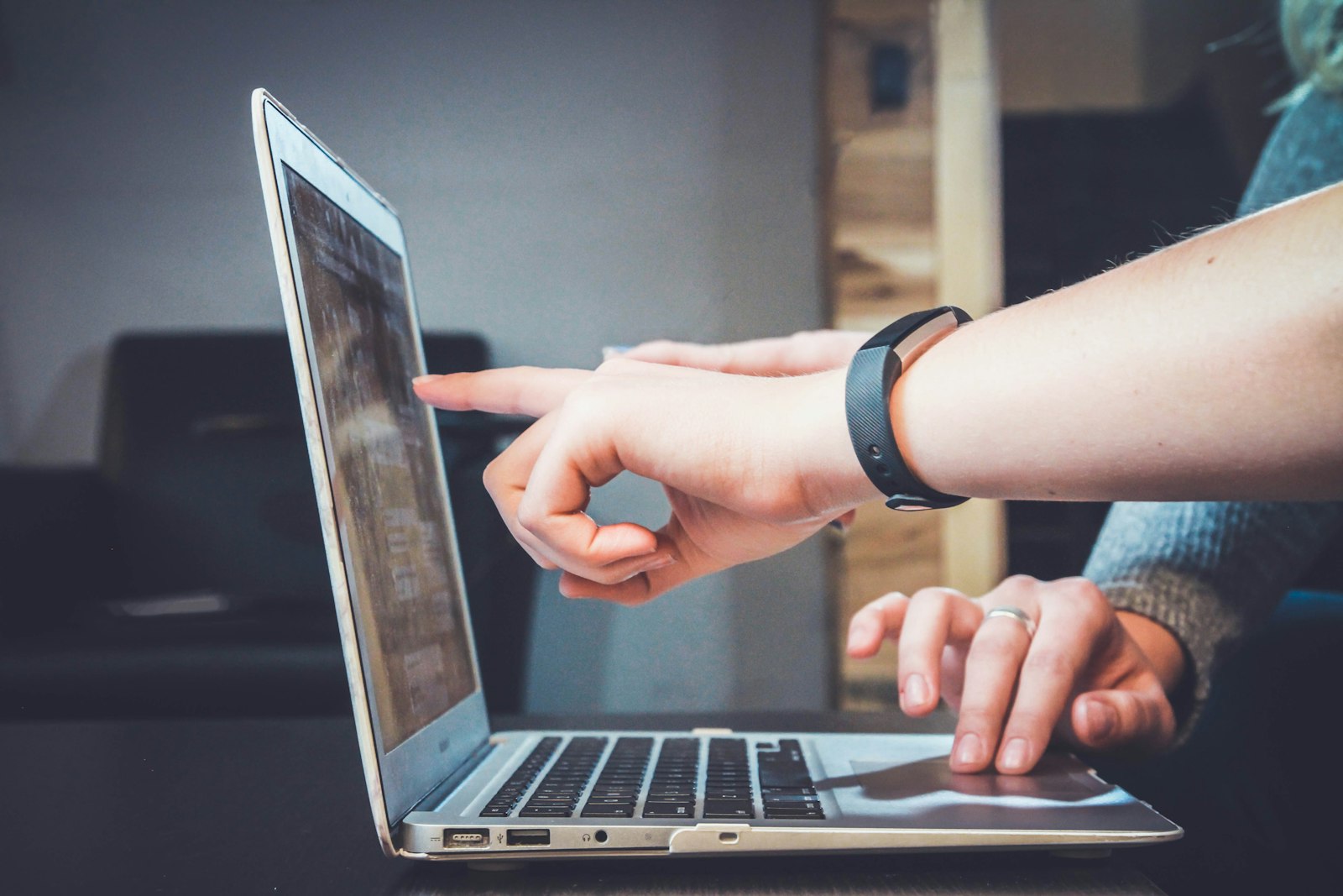 Hands pointing at a MacBook Air screen
