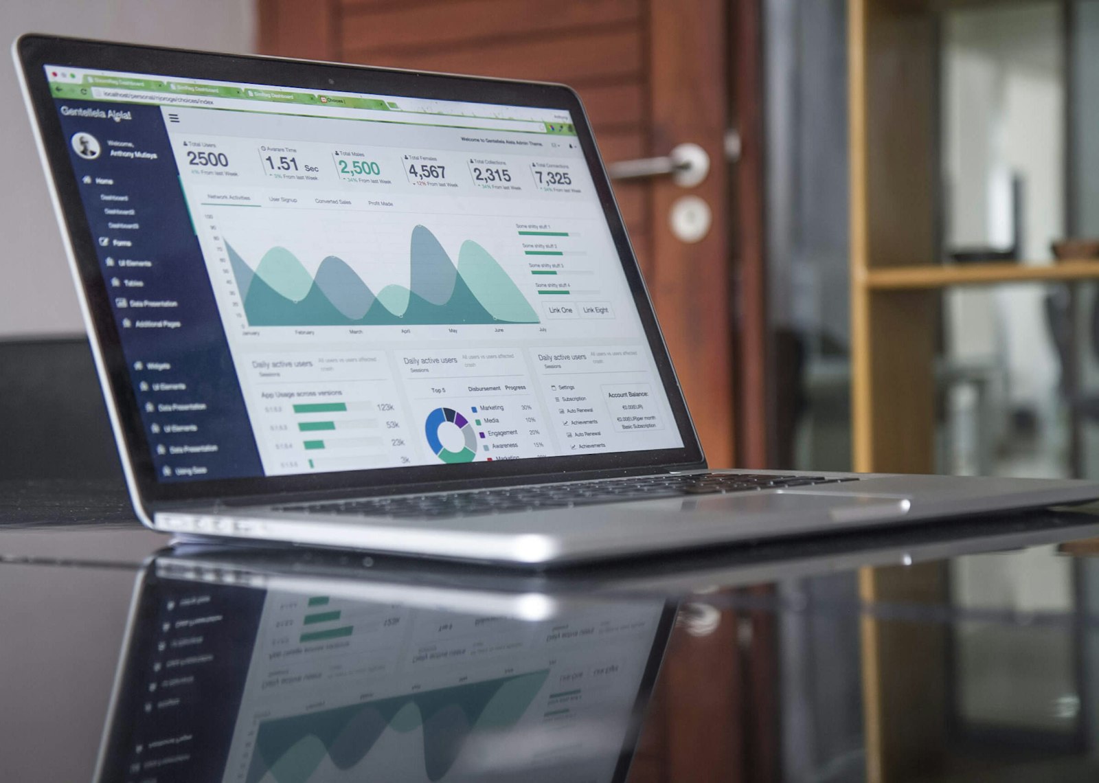 Silver MacBook on a glass table showing charts