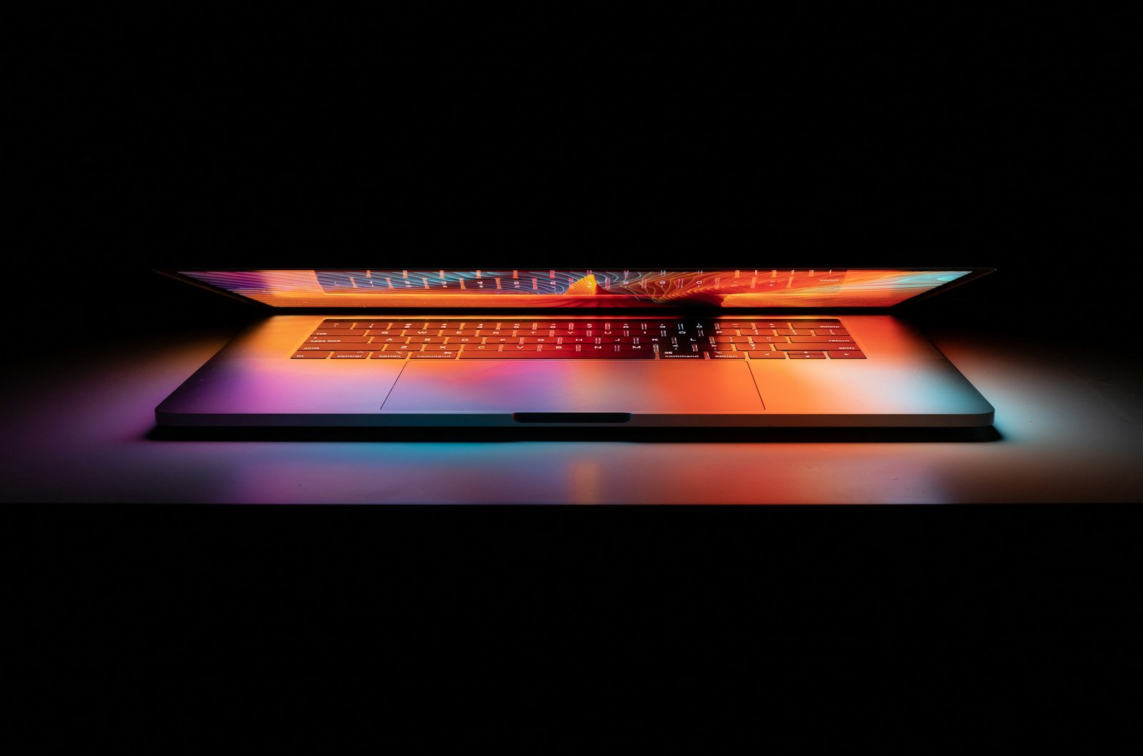 MacBook Pro seen from the front with a vivid screen in a dark studio