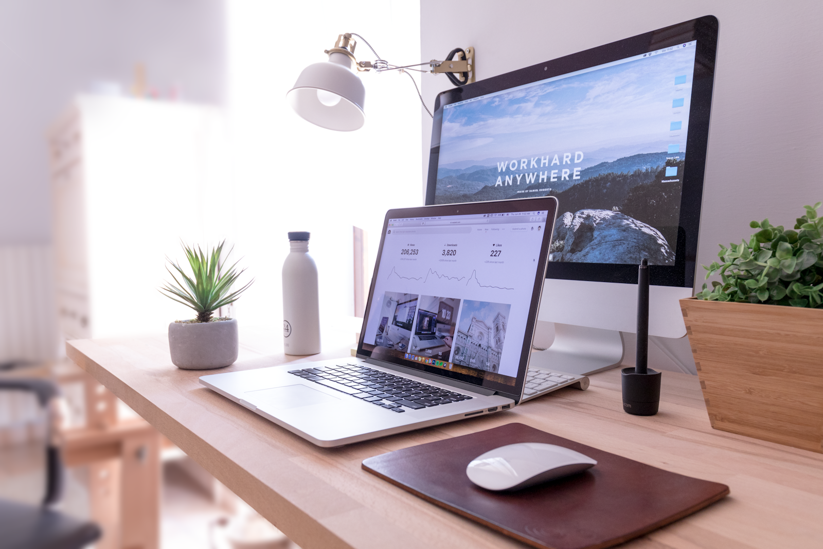 MacBook on a bright desk beside a large display