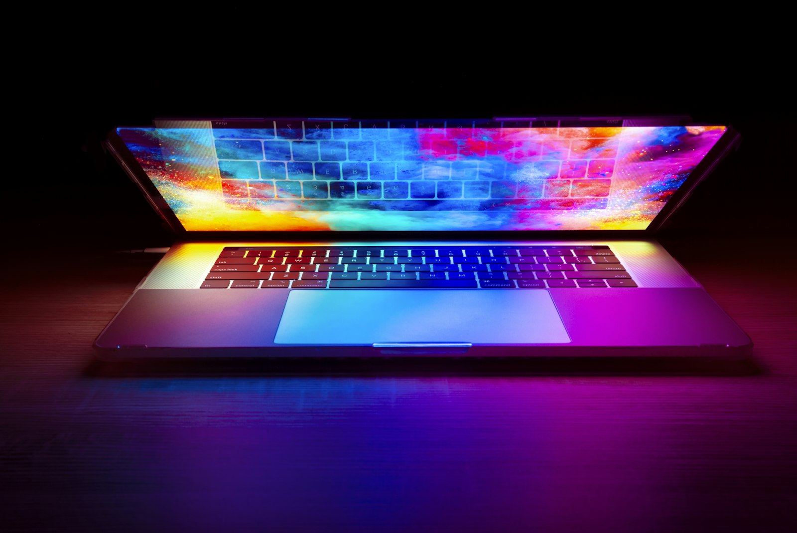 Open MacBook Pro with rainbow light across the keyboard and screen